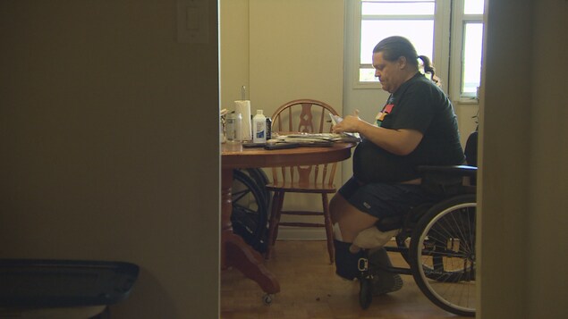 Ronald Hoppe est assis sur son fauteuil roulant et consulte des documents.