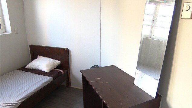 Une chambre meublée d'un lit simple et d'un bureau modeste Une chambre meublée d'un lit simple et d'un bureau modeste