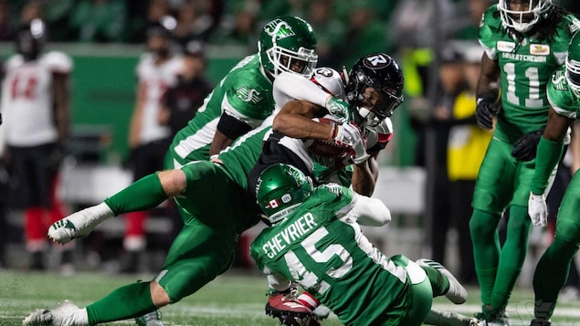 Deux joueurs en vert essaient de rabattre au sol un adversaire.