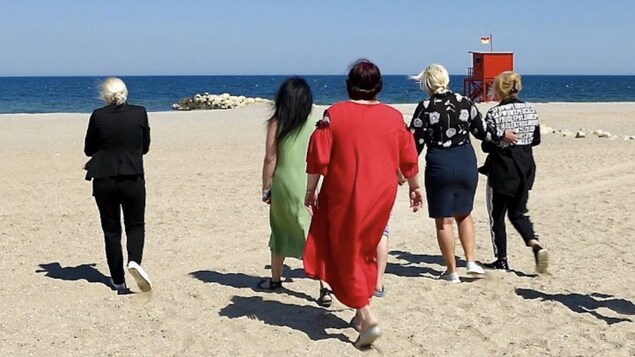 The women are walking on the beach.
