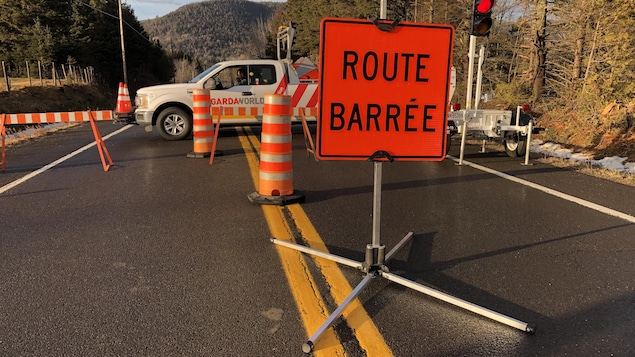 Un barrage routier et une pancarte où on peut lire "route barrée".