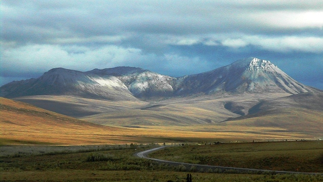 Plan large de la route avec au fond les montagnes aux sommets enneigés