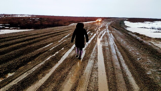 Une femme marche sur la route boueuse. Une femme marche sur la route boueuse.