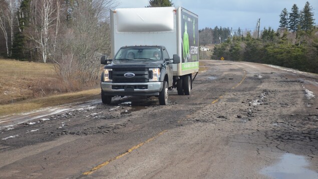 Un camion roule sur une route pleine de trous.