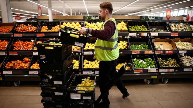 Un employé place des citrons dans les étals d'un supermarché.