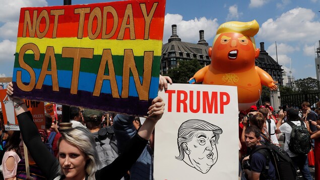 Une femme tenant une pancarte multicolore devant une foule de manifestants. Une femme tenant une pancarte multicolore devant une foule de manifestants.