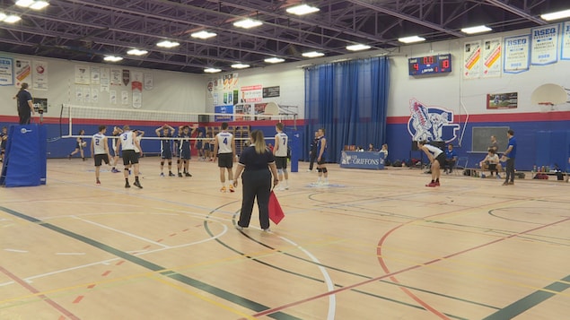 Des joueurs de volleyball de part et d'autre d'un filet lors d'un match dans un gymnase.