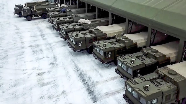 Une dizaine de chars militaires sortent d'un bâtiment.