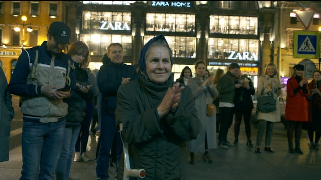 Une foule chante et tape des mains dans la rue.