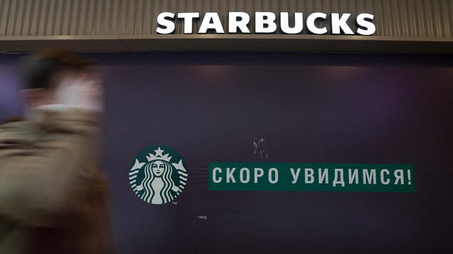 Un homme marche devant une enseigne Starbucks à Saint-Pétersbourg.