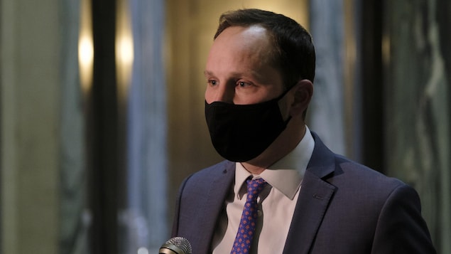 Ryan Meili parle aux médias en portant le masque.