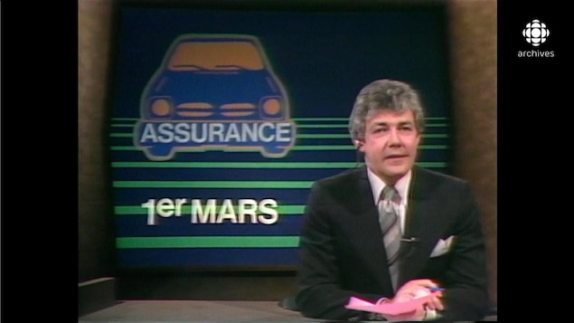 Normand Harvey devant une mortaise illustrant une automobile avec les inscriptions Assurance et 1er mars