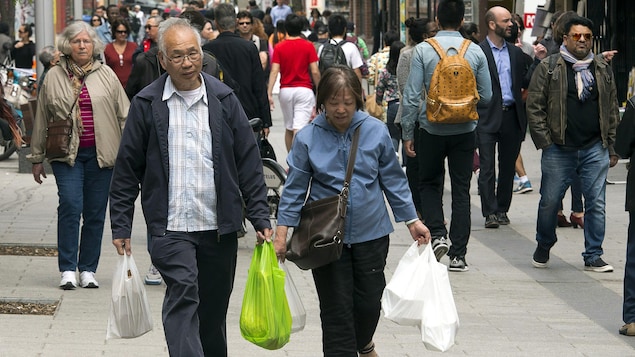 Des piétons transportent des sacs de plastique dans le quartier chinois de Montréal.