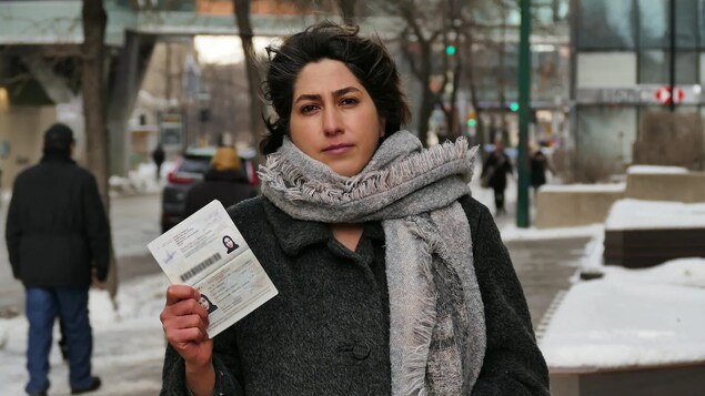 L'étudiante tient son passeport dans sa main dans le centre-ville de Winnipeg.
