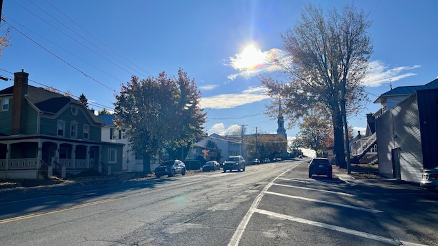UNe large rue bordée de maisons, d'arbres et d'une église. 
