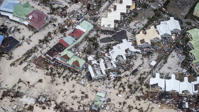 Une plage dévastée de la partie néerlandaise de l'île de Saint-Martin : des bâtiments ont été détruits, et des arbres balayés sur le sable. Une plage dévastée de la partie néerlandaise de l'île de Saint-Martin : des bâtiments ont été détruits, et des arbres balayés sur le sable.