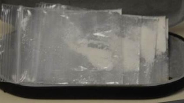 Gros plan de cinq petits sachets remplis d'une poudre blanche dans un étui brun. Gros plan de cinq petits sachets remplis d'une poudre blanche dans un étui brun.