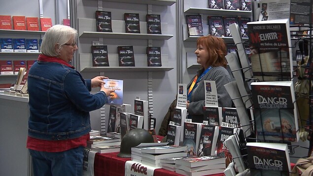 Une lectrice achète un livre au Salon du libre de la Côte-Nord.