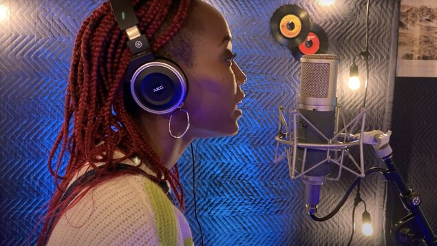 Samantha Nyenimana chante devant un microphone dans un studio d'enregistrement.