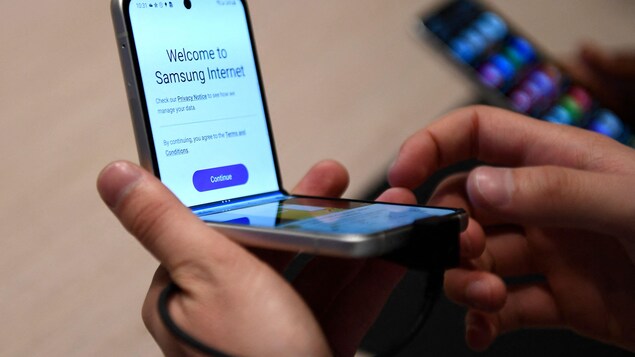 Un téléphone pliable de Samsung est ouvert dans une main et présente des termes d'utilisation.
