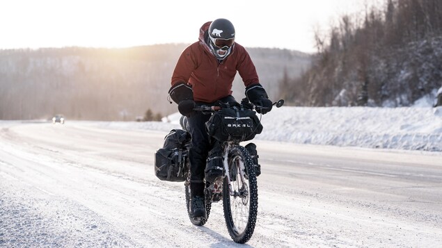 Samuel Lalande-Markon roule à vélo sur une route enneigée. Sa cagoule est gelée autour de sa bouche.