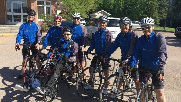 Un groupe de cyclistes sont sur leur vélo et sourient à la caméra. Un groupe de cyclistes sont sur leur vélo et sourient à la caméra.
