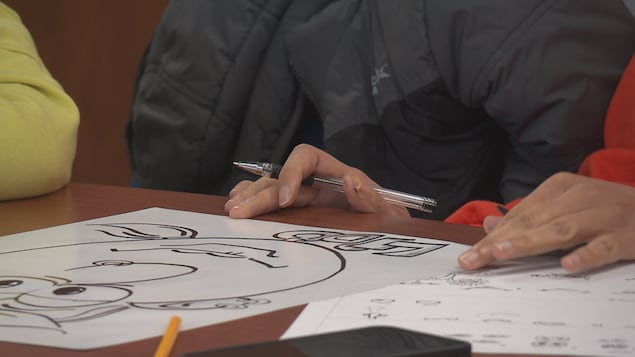Les mains d’une femme tiennent un crayon au-dessus d’un dessin.