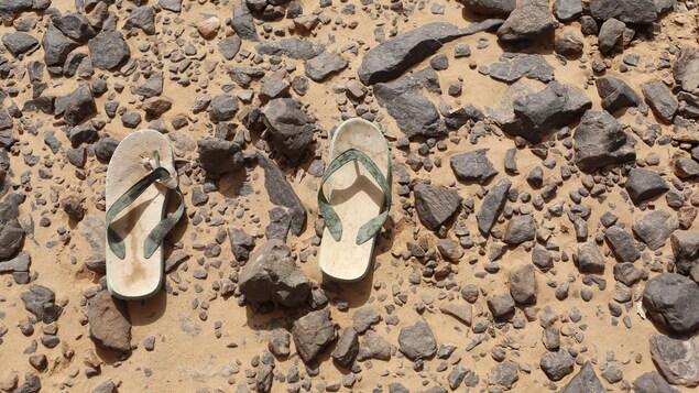 Des sandales gisent dans le sable et la roche. Des sandales gisent dans le sable et la roche.