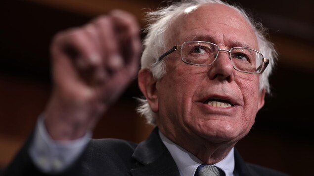 Bernie Sanders, le bras levé, s'adresse aux journalistes.