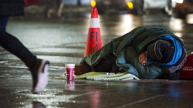 Un sans-abri sur un trottoir la nuit à Toronto.