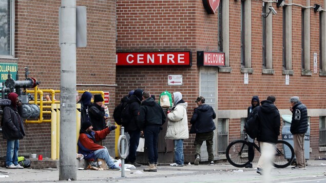 Des hommes attendent à l'entrée d'un refuge à Toronto.