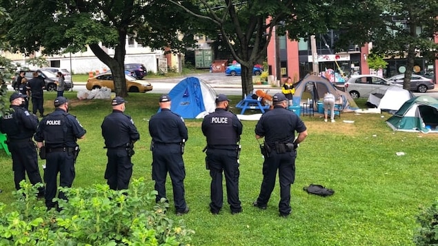 Les policiers en ligne surveillent les sans-abri qui ramassent leurs choses.