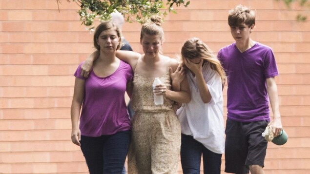 Quatre adolescents marchent ensemble dans l'herbe, l'air attristé. Certains semblent pleurer. Quatre adolescents marchent ensemble dans l'herbe, l'air attristé. Certains semblent pleurer.