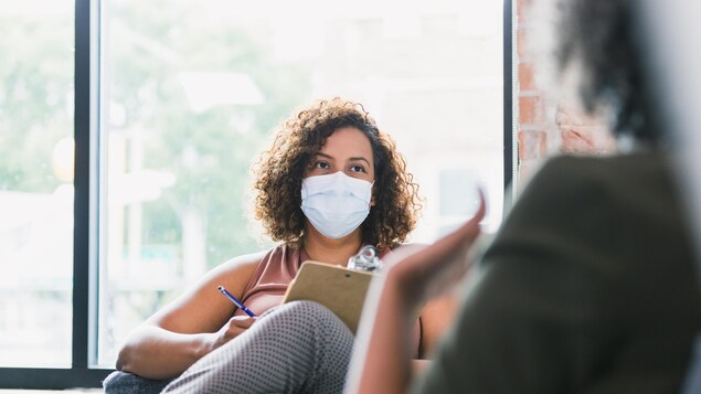 Une intervenante portant un masque de protection écoute un patient.