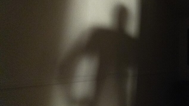 La silhouette d'un homme se dessine dans le cadre d'une porte