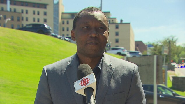 Un homme parle devant un hôpital.