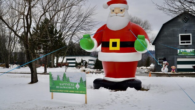 Une affiche de la Sapinière de la Mauricie avec un père Noël gonflable derrière.