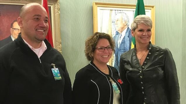 Trois personnes souriantes prennent la pause pour une photo dans le palais législatif de la Saskatchewan.