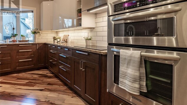 Une cuisine avec plan de travail en marbre et parquet de bois franc.