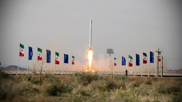 Un missile décolle dans un champ avec des drapeaux iraniens.