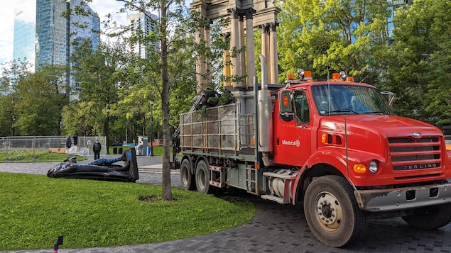 Un camion de la Ville de Montréal devant une statue à terre.