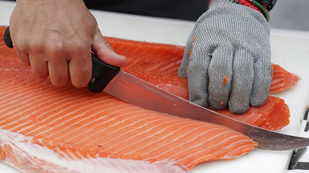 Un poissonnier tranche un morceau de saumon.