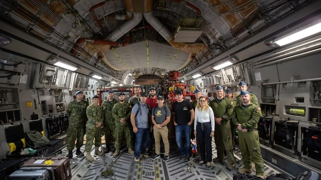 Un groupe de civils et de militaires posant ensemble à l'intérieur de l'avion de l'Armée canadienne.
