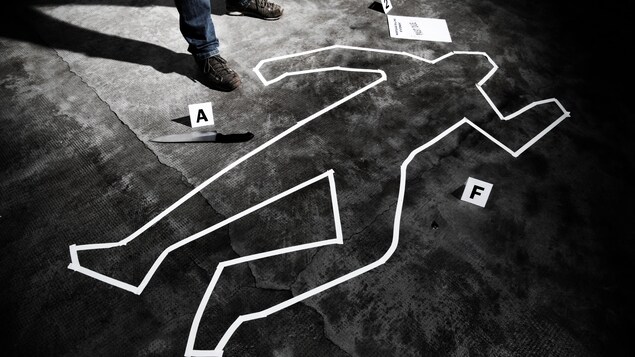 On voit en blanc le tracé d'un corps humain sur une scène de crime reconstituée.