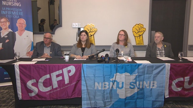 Les représentants syndicaux sont assis à une table avec des micros pour donner une conférence de presse.