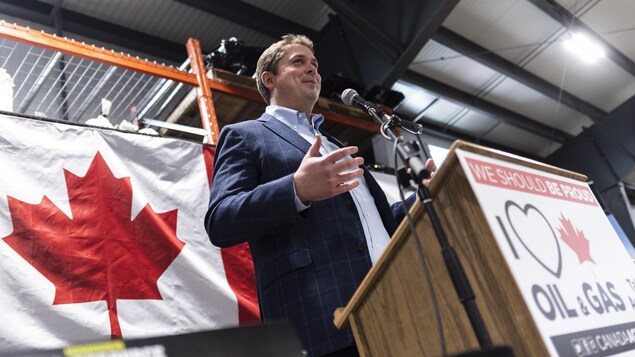 Un homme parle au podium devant un drapeau canadien.