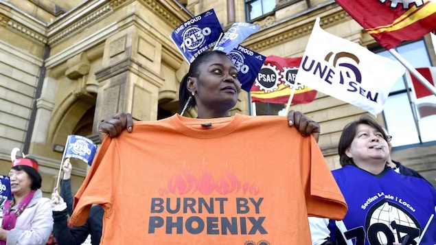 A member of Union Local 70130 holds a shirt during a protest against the Phoenix pay system outside the Office of the Prime Minister and Privy Council in Ottawa on Thursday, Oct. 12, 2017. 
