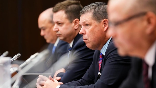 Four men in a parliamentary hearing.