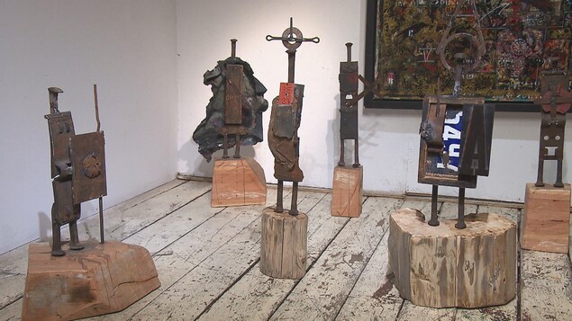 Des sculptures faites de retailles de métal sont exposées dans une salle de musée.