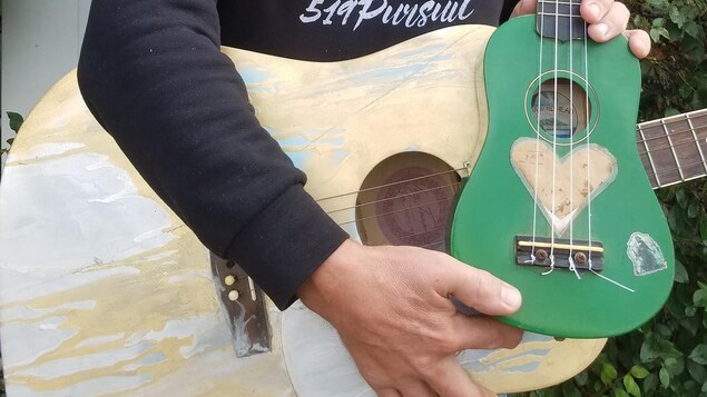 Sean Horell pose avec une guitare acoustique et un ukulélé.